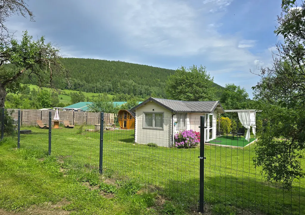 Ferienhaus und eingezäunter Garten vor den Bergen